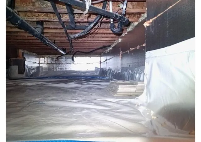 Crawl space vapor barrier with rigid foam on walls and plumbing visible - NY Energy Project