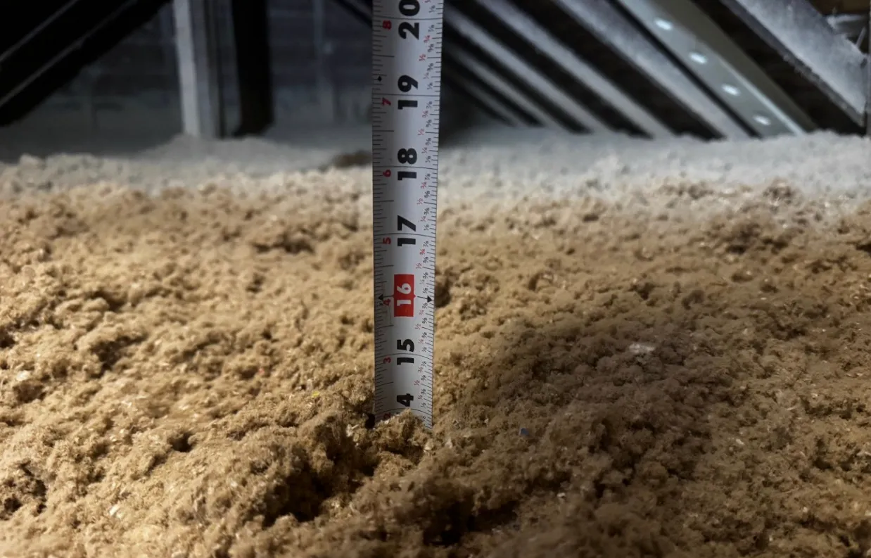 Depth gauge measuring 16 inches of blown-in cellulose insulation in NYC attic - NY Energy Project