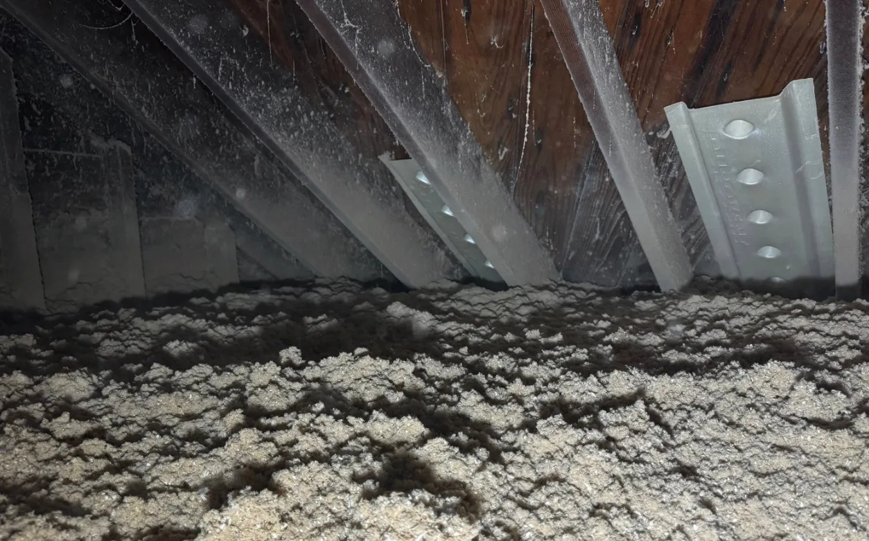 Cellulose insulation covering attic floor between metal framing and rafters - NY Energy Project