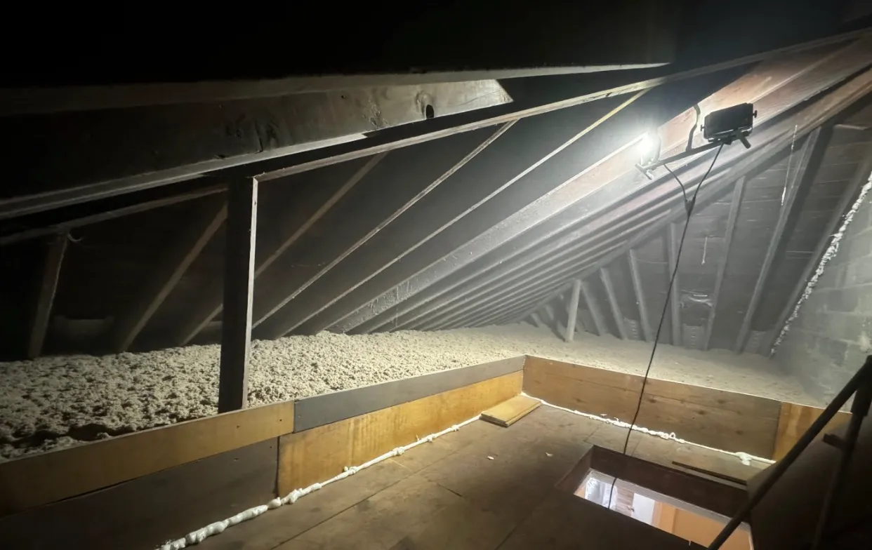 Well-lit attic with metal bracing and cellulose insulation on floor - NY Energy Project completed job