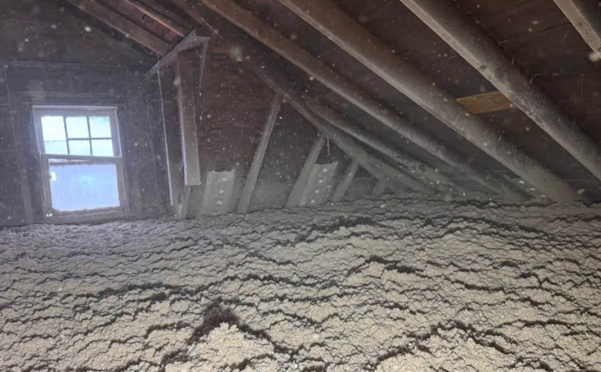 Attic insulation covering floor and walls near window with full coverage - NY Energy Project