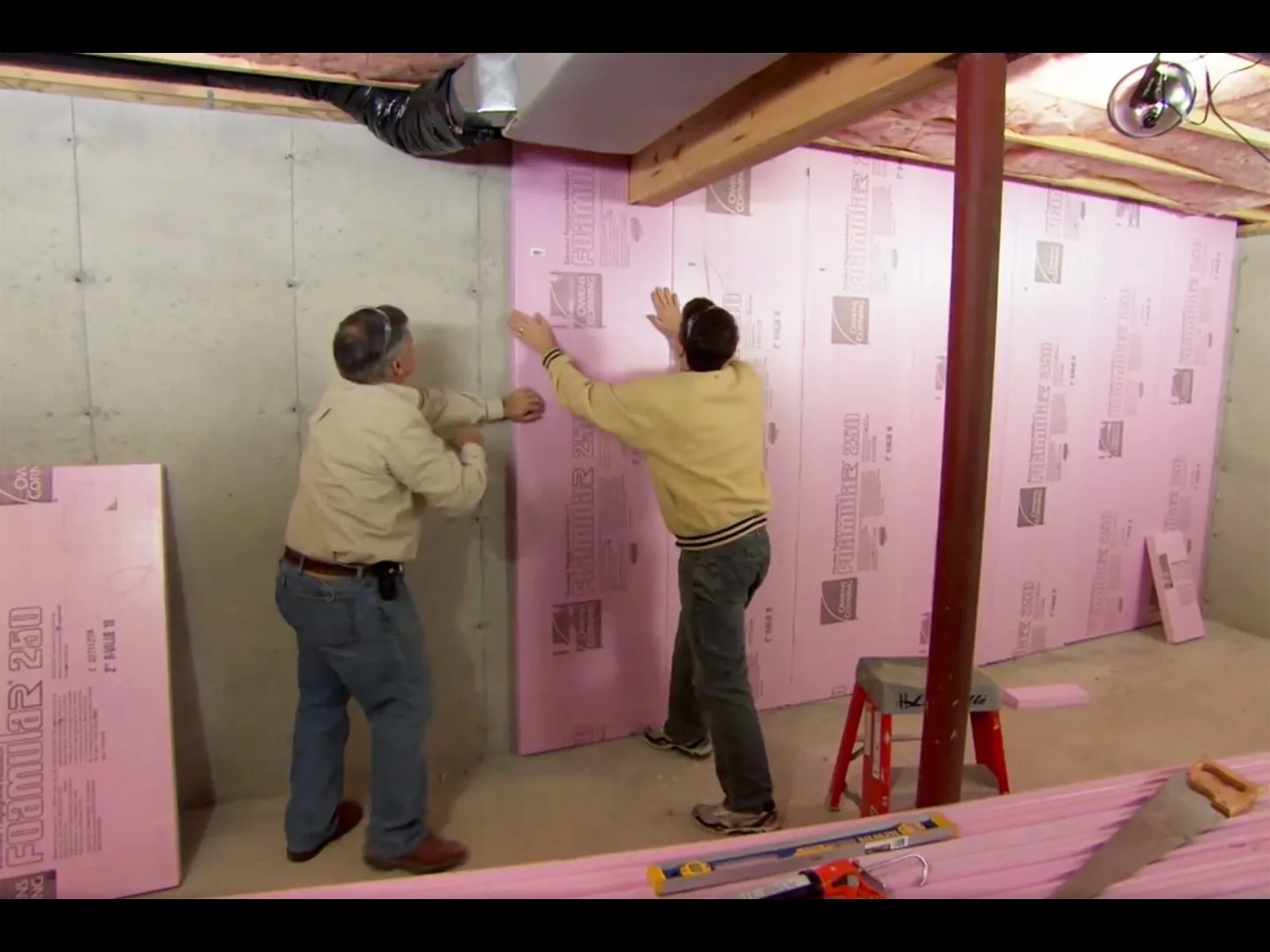Workers installing rigid foam insulation on basement walls