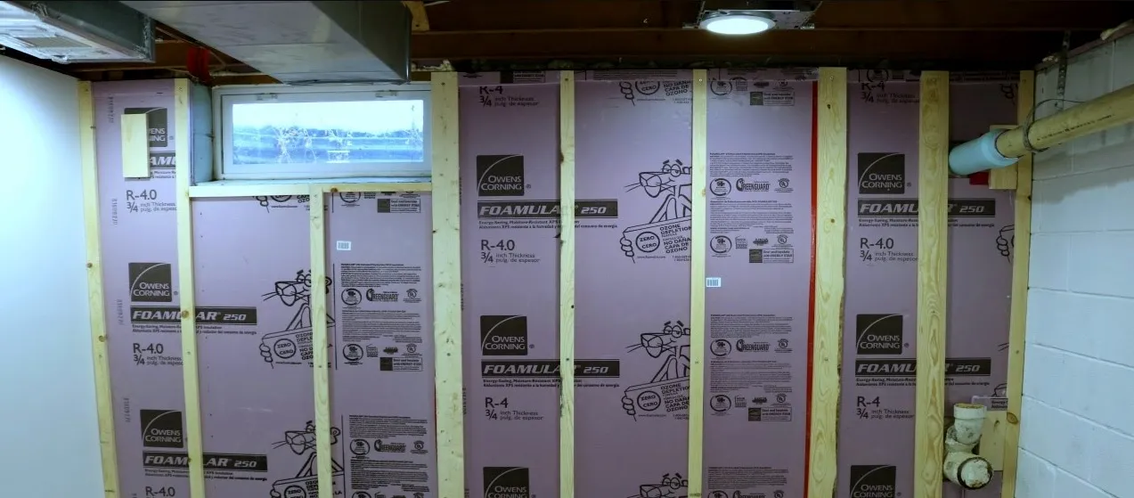Rigid foam insulation boards installed between studs on basement wall