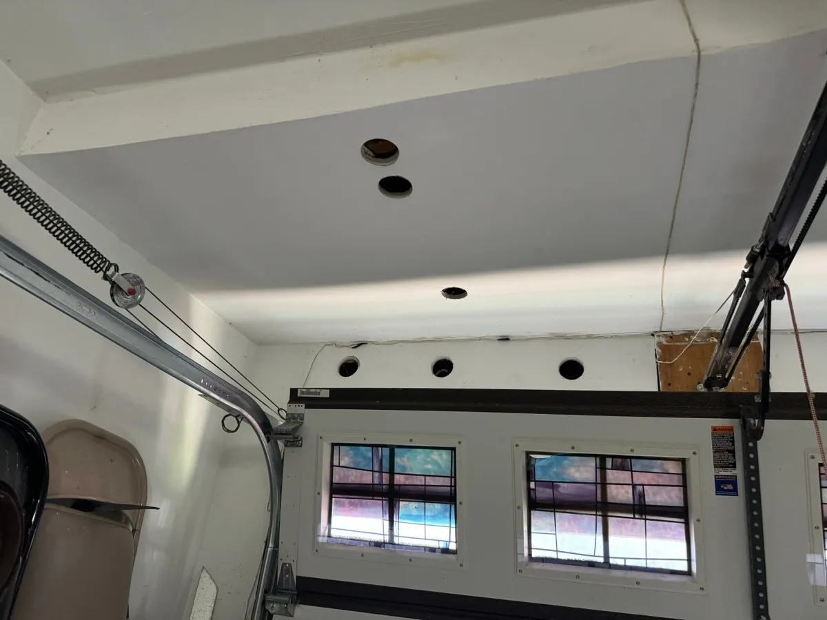 Garage ceiling and wall with drill holes near garage door for insulation blowing