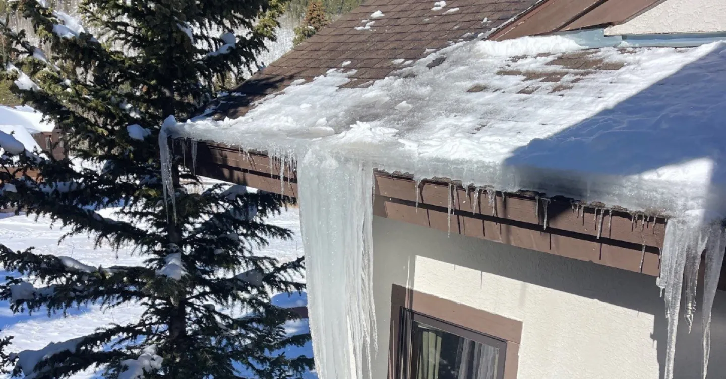 Ice dam with icicles forming on a residential roof