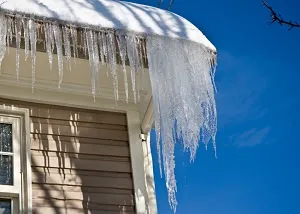 Icicles hanging from residential roof eave caused by ice damming