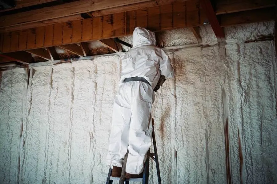 BPI-certified installer applying spray foam insulation to basement walls