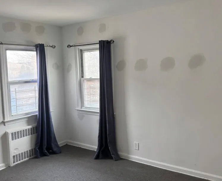 Gray bedroom with spackle patches over drill holes after wall insulation installation - NY Energy Project